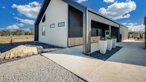A modern building with a large garage door, a number '4517' on the side, and a paved driveway with gravel and large rocks. - Modern Cabin Near Cheney Lake W Pool and Hot Tub - Holiday Home (Pretty Prairie)