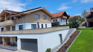 A modern two-story house with a garage, a covered patio, and a well-maintained lawn.