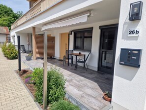 A modern building with a covered patio, a wooden door, and a mailbox.