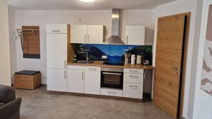 A compact kitchen with white cabinets, a built-in oven, and a wooden door.