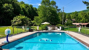 A rectangular swimming pool with a tiled edge, a basketball hoop, and a small covered seating area. - Cold Spring Lodge - Cabin 5 (Big Indian)