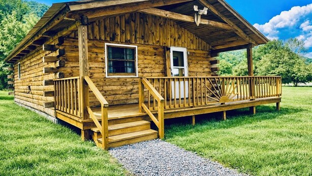 A wooden cabin with a porch, a set of stairs, and a gravel path leading to it.