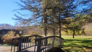 Un ponte di legno in un parco, con alberi e un edificio sullo sfondo.