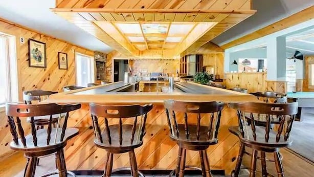 A wooden interior with a central island and bar stools.