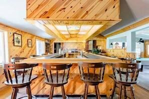 Un interior de madera con una isla central y taburetes de bar.