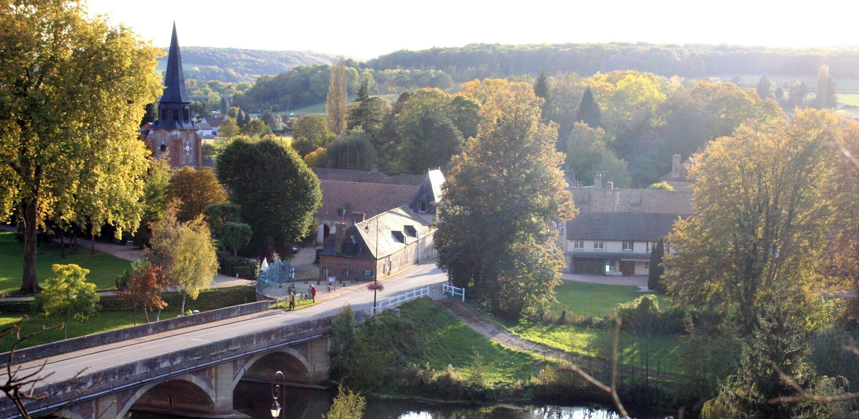 Un pont enjambant une rivière, avec une église et des immeubles d’habitation en arrière-plan.
