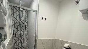 Un baño moderno con un lavamanos grande, un bidé, inodoro y una zona de ducha con puerta de vidrio de diseño geométrico.