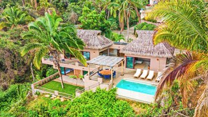 A modern resort with two thatched-roof villas, a swimming pool, and lush tropical vegetation. - Casa Ventana al Mar San Xoaquin (Puerto Vallarta)