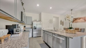 Una cocina moderna con una isla grande, electrodomésticos de acero inoxidable y un comedor con sofá y mesa.