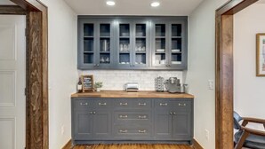 Une cuisine avec des meubles de couleur gris foncé, un plan de travail en bois et un dosseret de carrelage blanc.