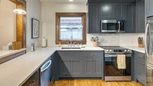 Une cuisine moderne avec des meubles de couleur gris foncé, un réfrigérateur en acier inoxydable, un four à micro-ondes et une cuisinière.
