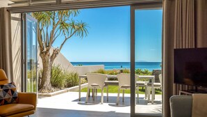 Een moderne woonkamer met een glazen deur die leidt naar een balkon met uitzicht op de oceaan.