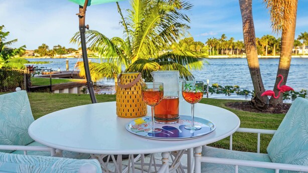 A round table with a white tablecloth, two glasses of amber liquid, a pitcher, and a decorative tray. - The Clarke Collection-Villa Flamingo - Waterfront (Lake Clarke Shores)