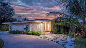 A modern house with a covered porch, a paved driveway, and lush landscaping. - The Clarke Collection-Villa Flamingo - Waterfront (Lake Clarke Shores)