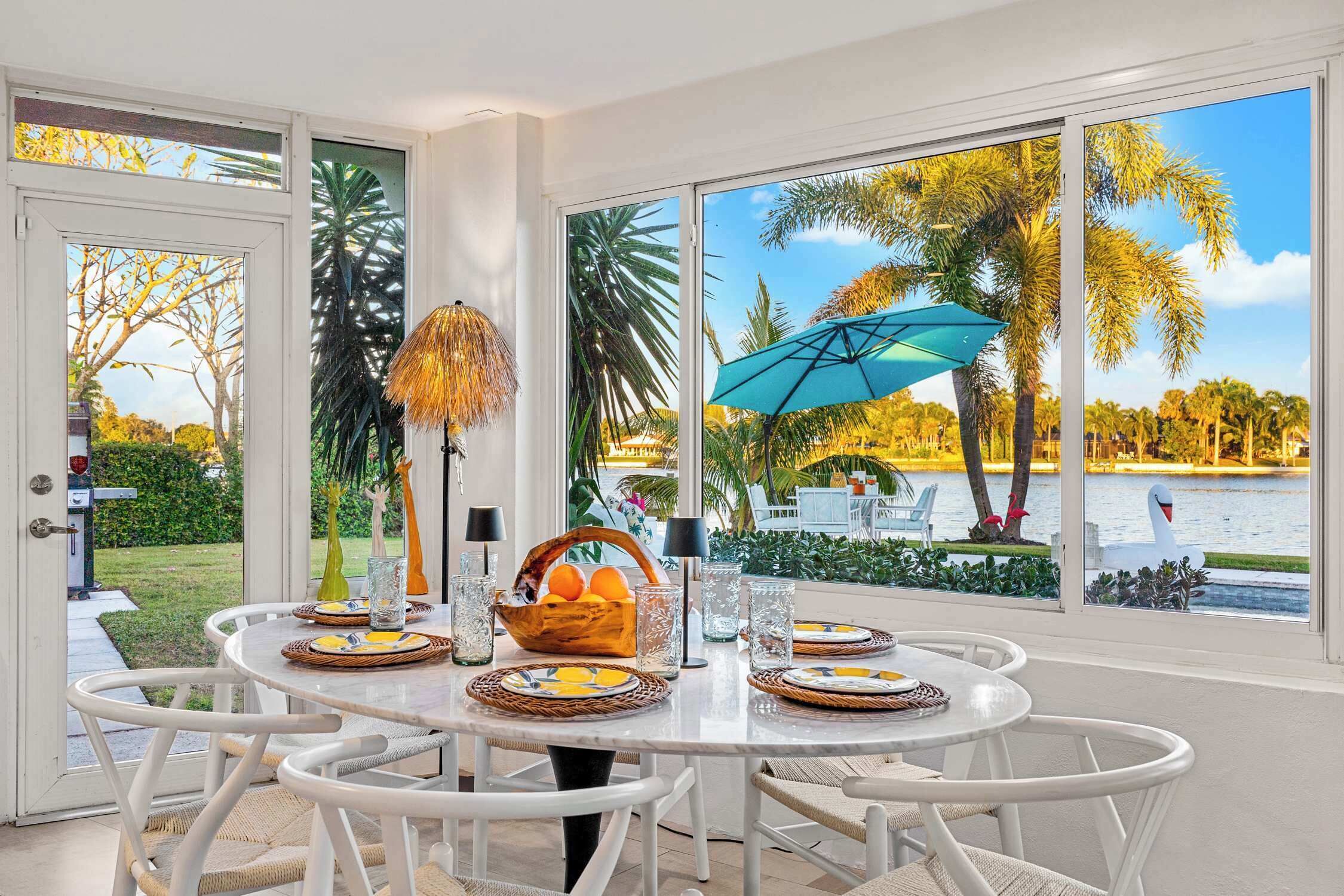 A dining area with a large window view of a lake and palm trees.