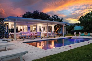 A covered outdoor area with a pool, lounge chairs, and a swan float.