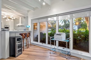 A modern kitchen with a built-in oven, a coffee machine, and a glass cart with a printer.