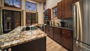 A modern kitchen with a large island, wooden cabinets, and stainless steel appliances.