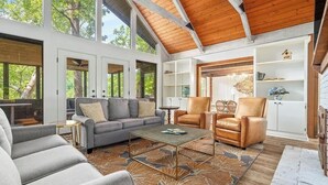 Un salon spacieux avec un haut plafond, de grandes fenêtres et un coin salon confortable.