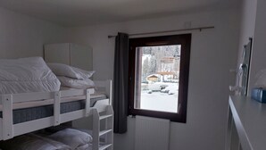 A small, clean room with bunk beds, a window with a view of a snowy landscape, and a radiator. - Les Lodges, Apartment Plagne Centre-La Plagne-Tarentaise, 2 rooms 5 people (La Plagne-Tarentaise)