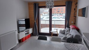 A modern living room with a dining table, sofa, and TV. - Les Lodges, Apartment Plagne Centre-La Plagne-Tarentaise, 2 rooms 5 people (La Plagne-Tarentaise)