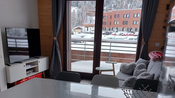 A modern dining area with a large table, chairs, and a television on a white cabinet. - Les Lodges, Apartment Plagne Centre-La Plagne-Tarentaise, 2 rooms 5 people (La Plagne-Tarentaise)