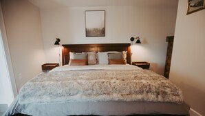 Ein großes Bett mit flauschiger weißer Bettdecke, zwei Nachttische mit Lampen und ein gerahmtes Bild an der Wand.