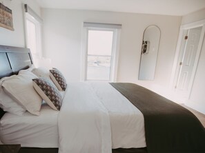 A bedroom with a bed, pillows, a window, and a door. - Apt. # 4 - Goldsmith's River Front Inn - Flathead Apartment (Missoula)
