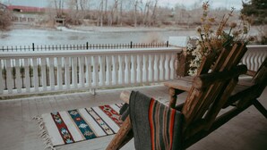 A wooden bench with a woven seat cushion, a wooden table, and a decorative vase with dried flowers.