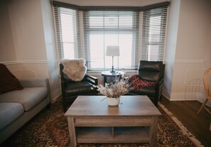 A living room with a sofa, a coffee table with a vase, and a lamp.