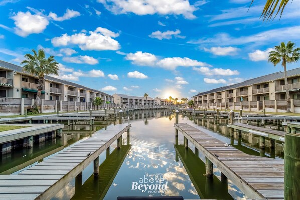 A waterfront hotel with a canal, wooden walkways, and palm trees.