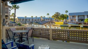 A deck with outdoor seating overlooking a marina and buildings.