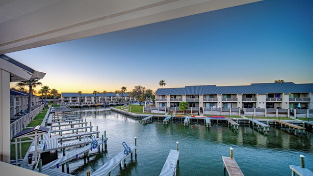 A marina with docked boats, a waterway, and a row of multi-story buildings with balconies. - The Salty Seahorse | Pet-Friendly Canal Retreat w/ Grill & Deck (Rockport)
