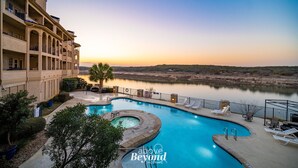 A hotel with a swimming pool, outdoor seating, and a view of a lake at sunset. - Lakeview & Pool View on an Island with Sauna & Spa (Lago Vista)