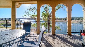 A wooden deck with a table and chairs, overlooking a body of water and distant landscape.