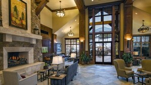A spacious lobby with a stone fireplace, comfortable seating, large windows, and a view of the outdoors. - Spring Break in Breckenridge! Ski in/out on Peak 7 (Breckenridge)