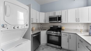 A modern kitchen with white cabinets, a built-in microwave, a stove, and a dishwasher.