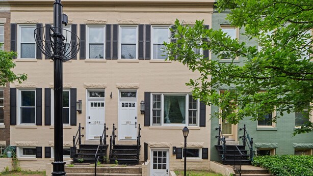 A row of townhouses with a central entrance, steps leading up to the door, and a street lamp in the foreground.