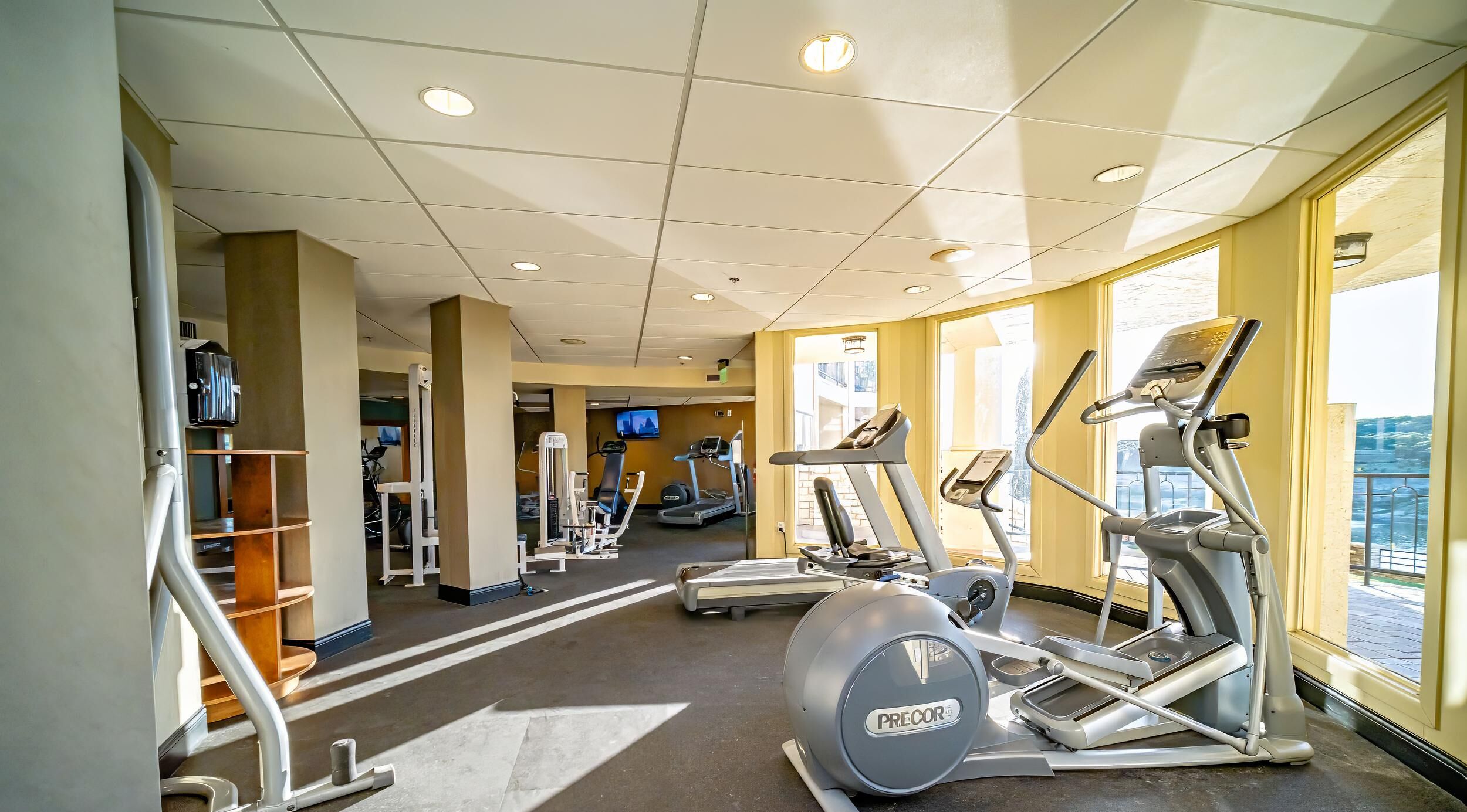 A gym with various exercise equipment, a water dispenser, and a TV screen.