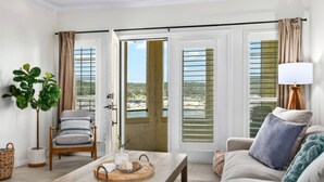 A modern living room with a wooden coffee table, a cushioned sofa, a chair, and a potted plant. - Island Summer Sunrises | Spa | Eats | Last Minute Deals! (Lago Vista)