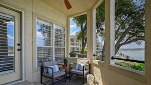 A balcony with two chairs and a small table, overlooking a body of water and buildings. - Island Summer Sunrises | Spa | Eats | Last Minute Deals! (Lago Vista)