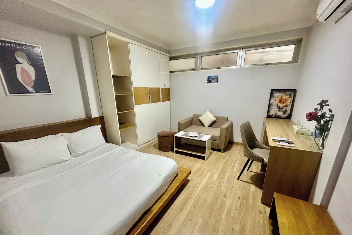 Quarto de hotel com cama, sofá, escrivaninha e guarda-roupa.