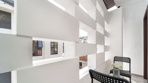 Ein modernes Interieur mit weißen Wänden, einer schwarzen Metallbank und einem kleinen Tisch mit einer Vase.