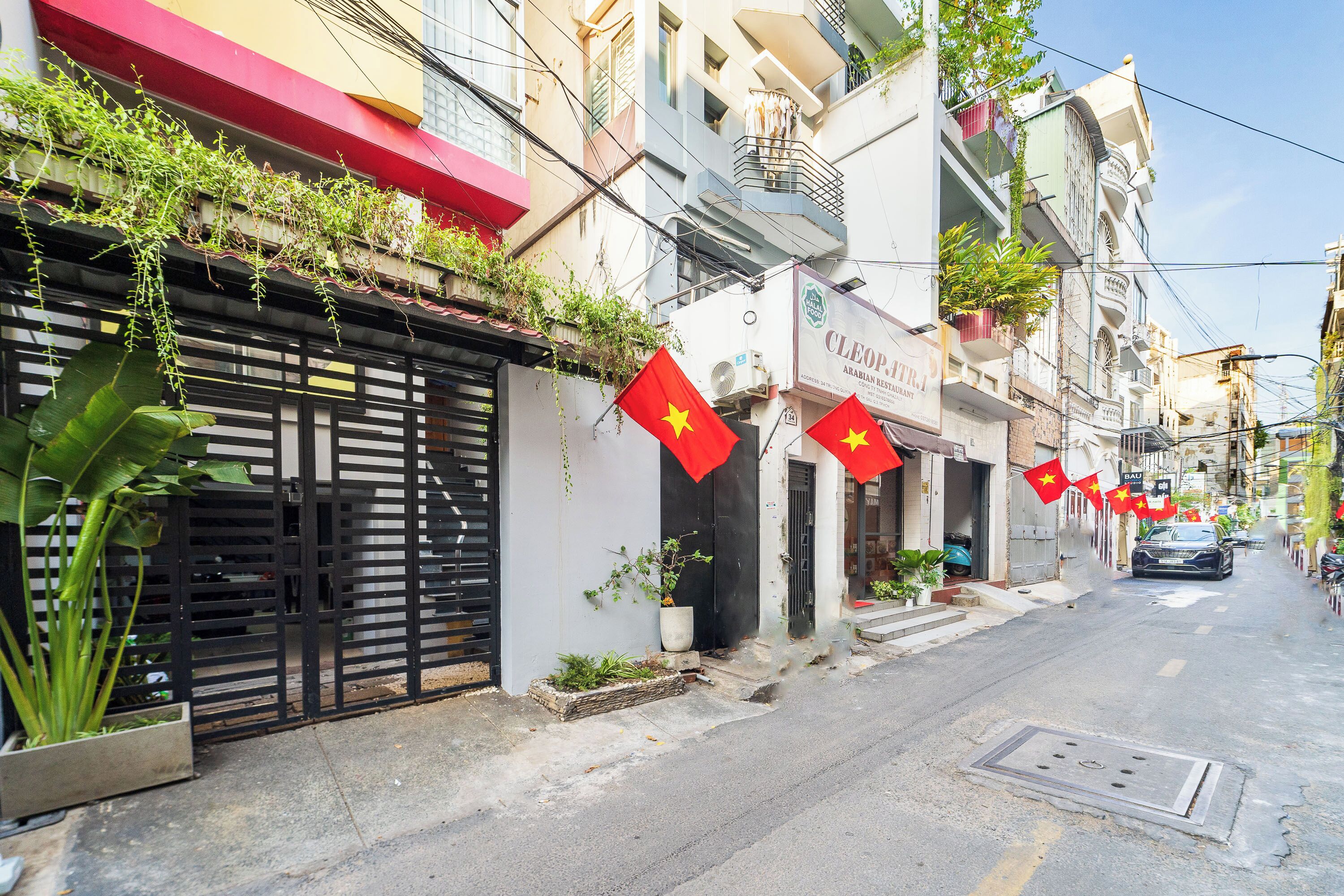 A street view with a restaurant named "CLEOPATRA ARABIAN RESTAURANT" on the corner, featuring a red awning and a signboard.