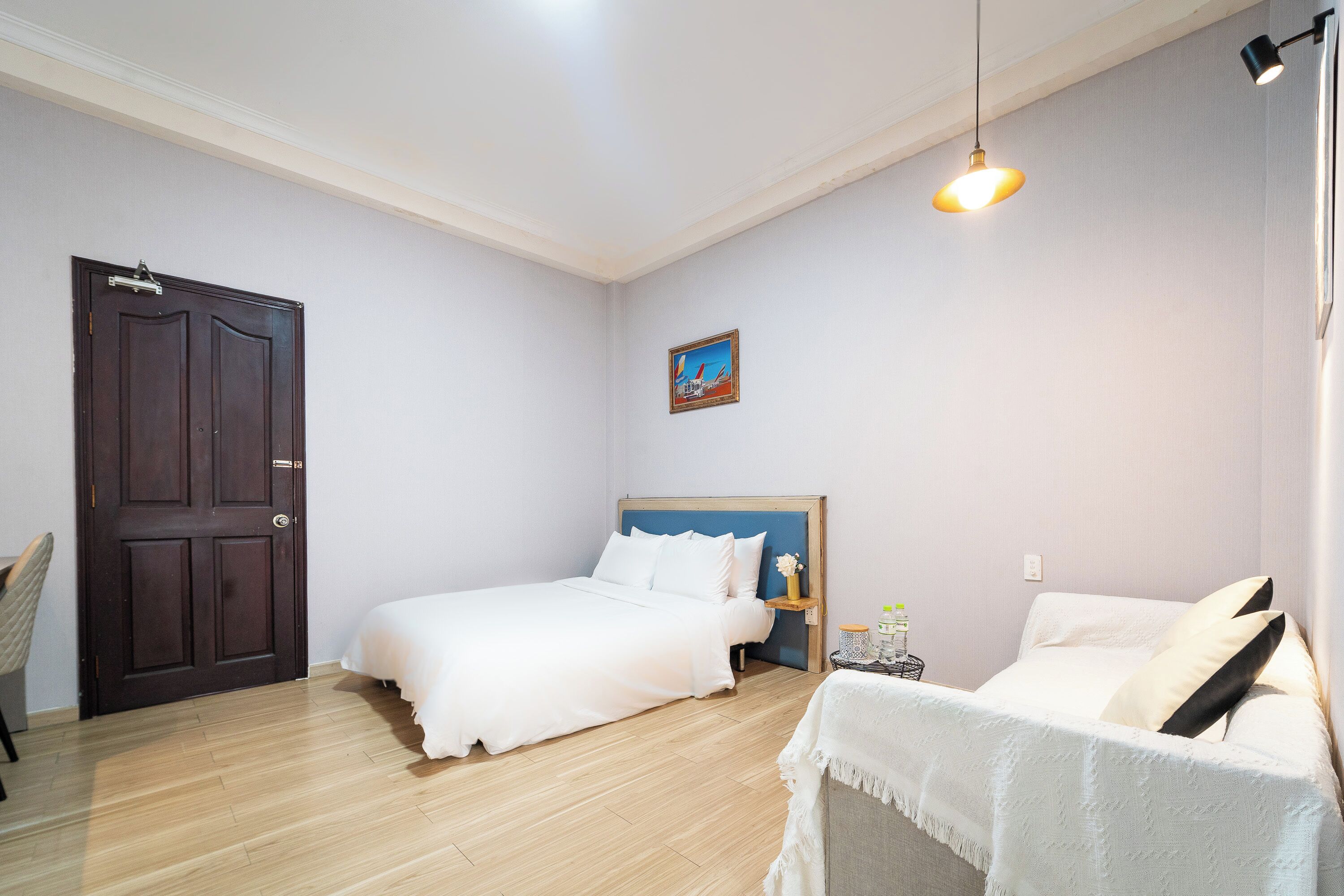 A bedroom with a bed, bedside table, lamp, and a door.