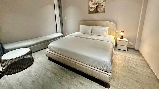 Ein modernes Schlafzimmer mit einem großen Bett, einer Bank am Fenster und einem kleinen runden Tisch.