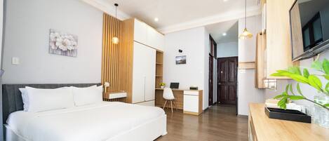 A modern bedroom with a bed, a desk, and a TV.