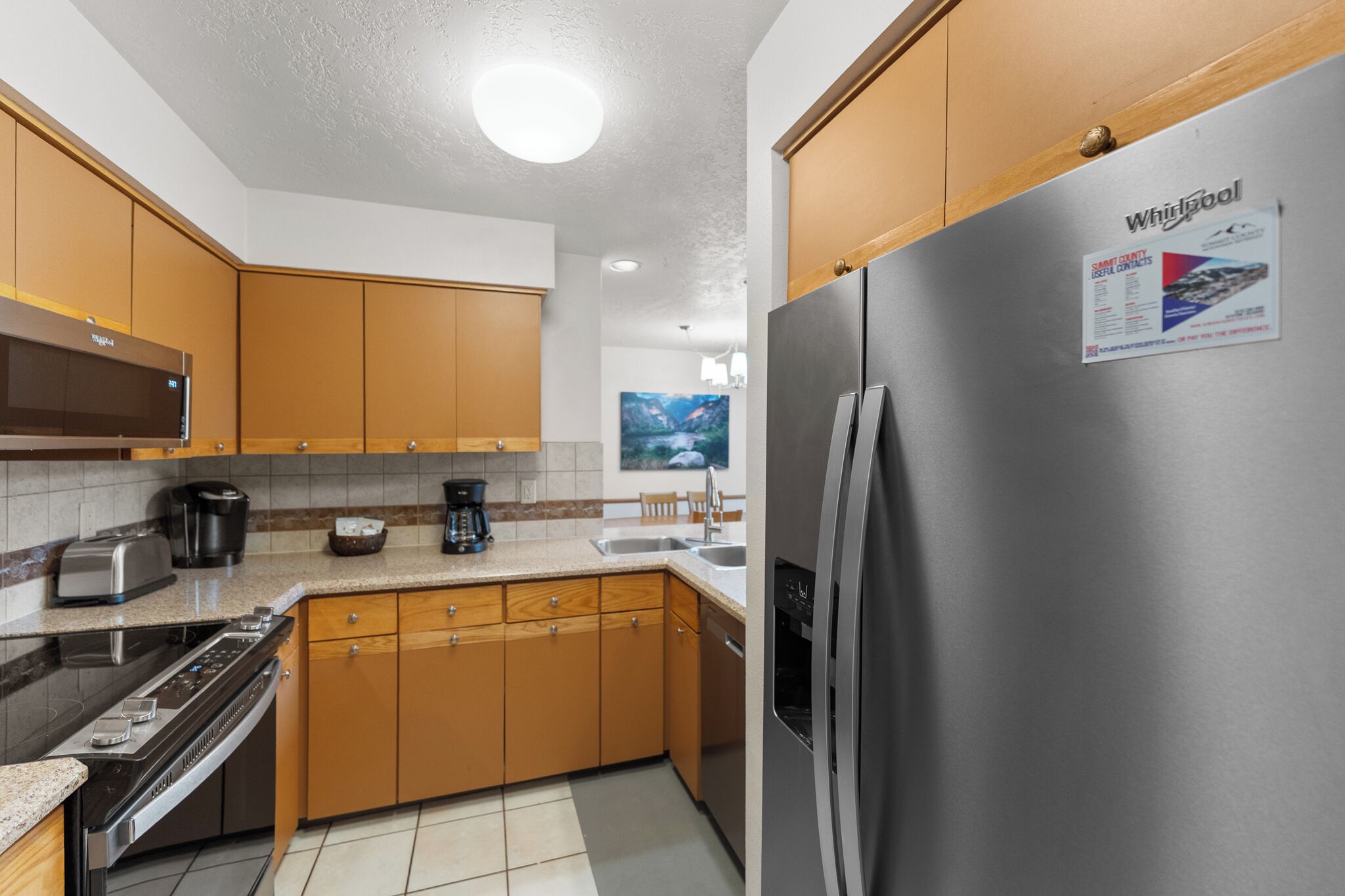 Una cocina moderna con armarios de madera, electrodomésticos de acero inoxidable y un refrigerador Whirlpool.