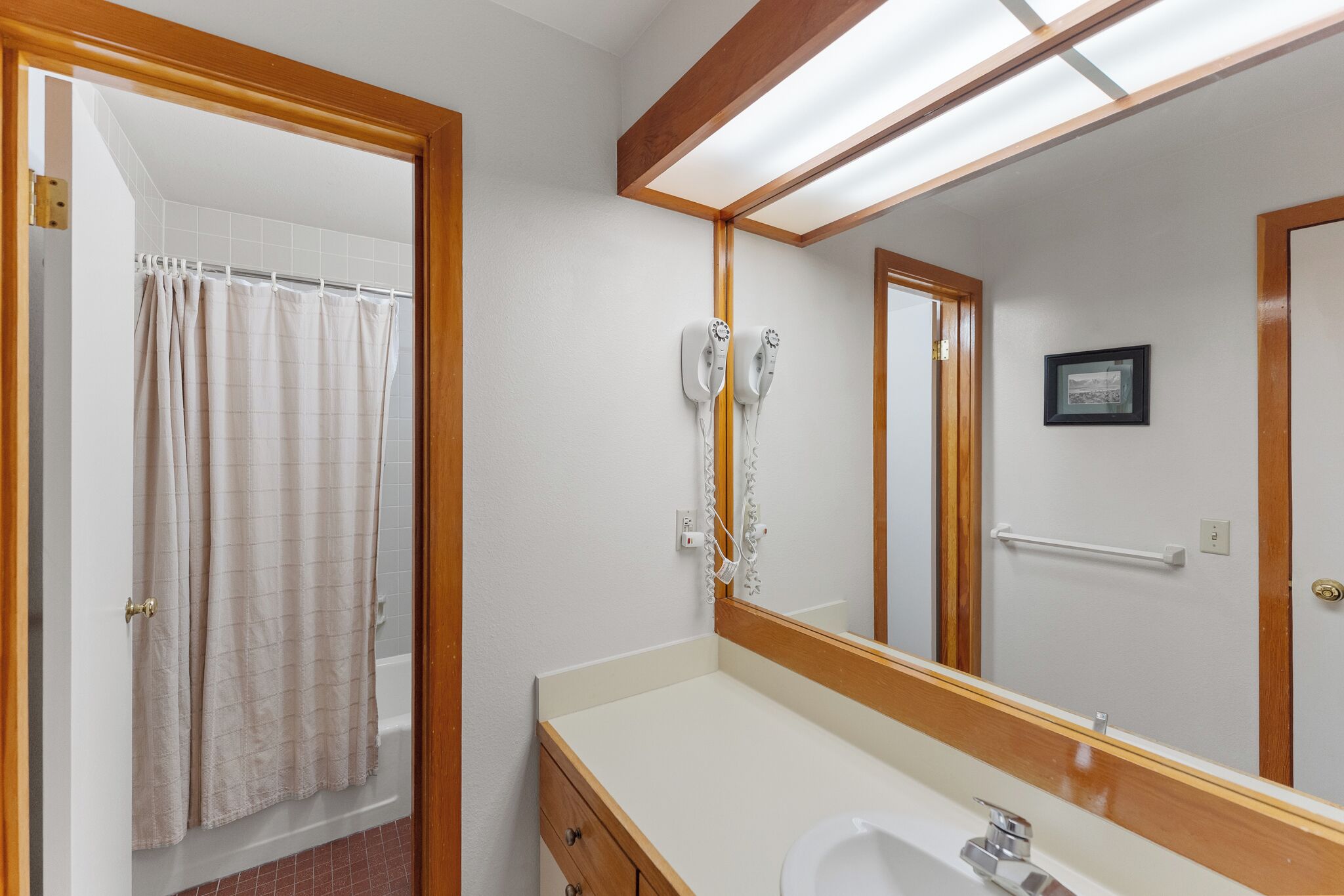 Une salle de bain avec un rideau de douche, un lavabo, un miroir et un porte-serviettes.