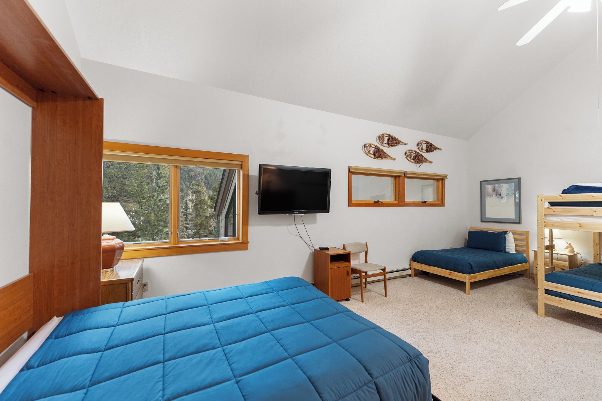 A bedroom with a large window, a television, bunk beds, and a desk.